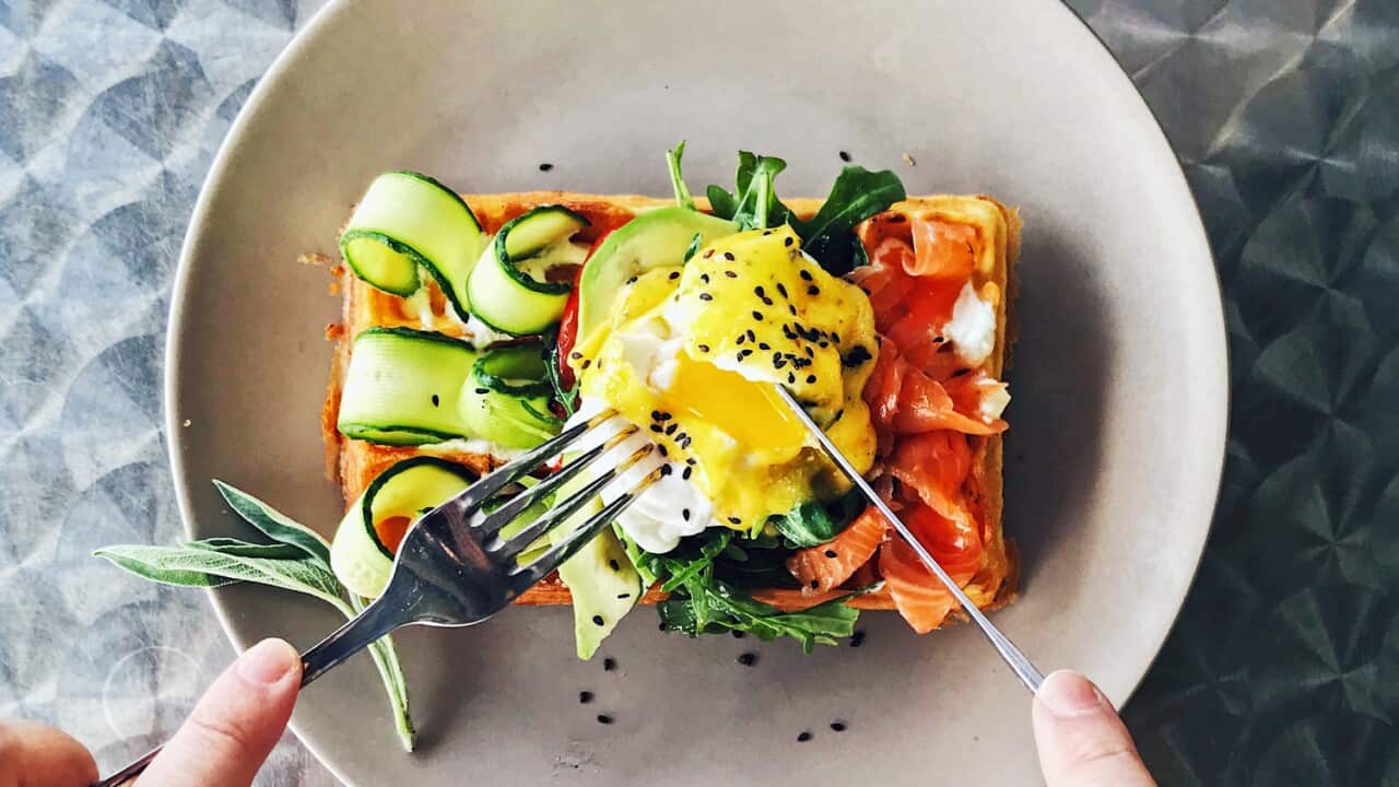 Eating brunch with waffle, avocado, cucumber, salmon and poached egg, personal perspective