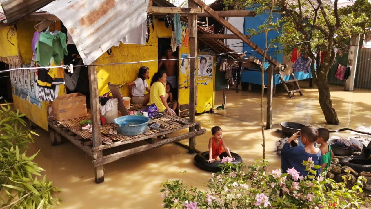 Villagers wade through water next to a flooded home on Christmas day.