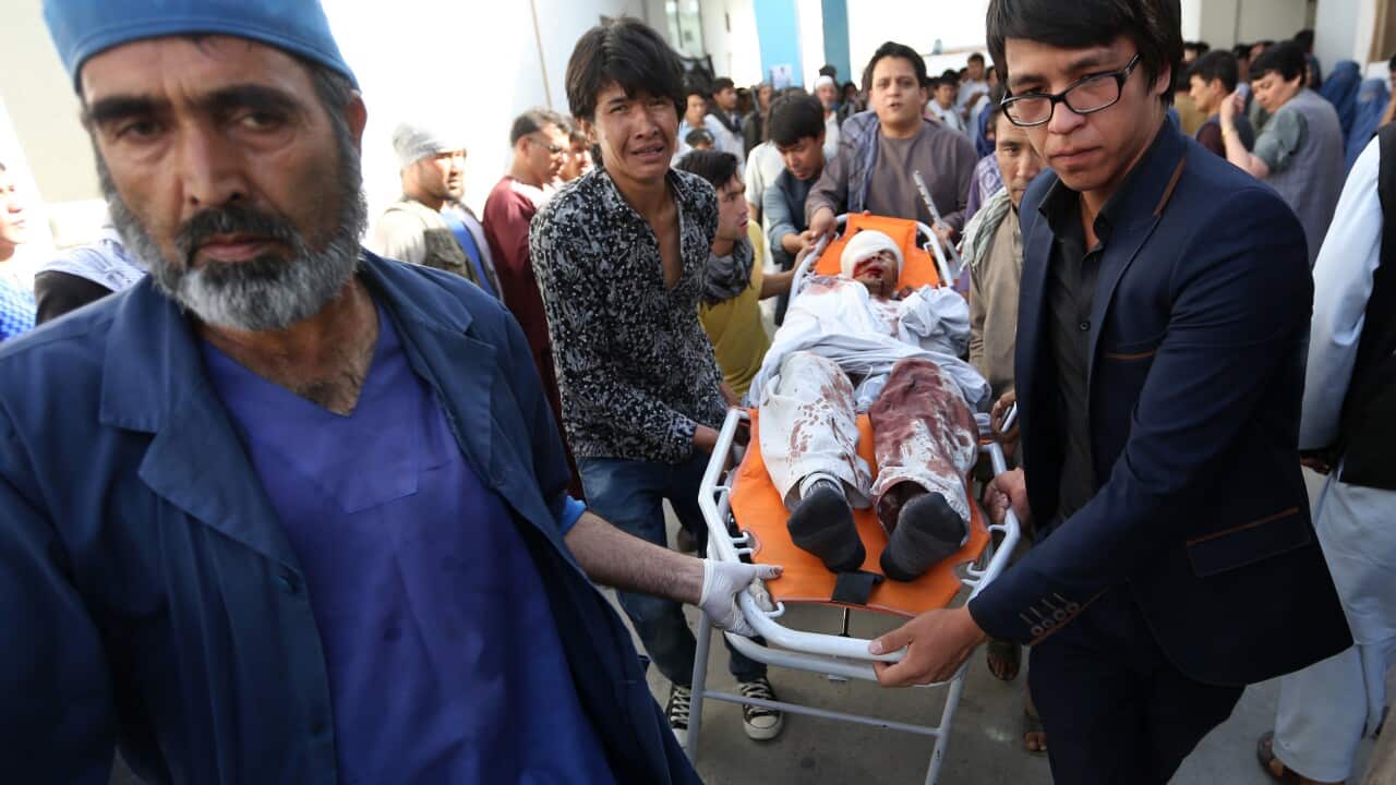 Afghans help a man who was injured in a deadly explosion that struck a protest march by ethnic Hazaras, at a hospital in Kabul