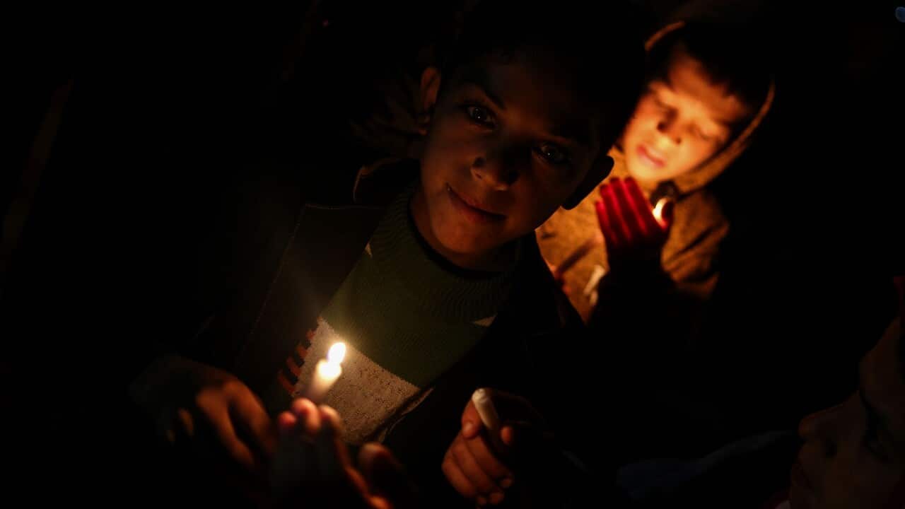 Palestinian youths hold candles in Gaza city