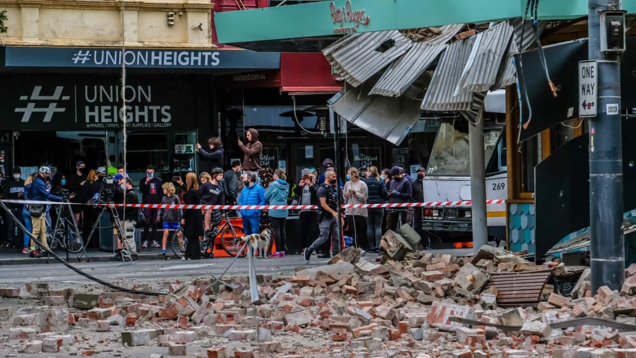 People forced out of building by the earthquake together with media are looking at the damage to Betty's Burgers & Concrete Co building during the aftershocks
