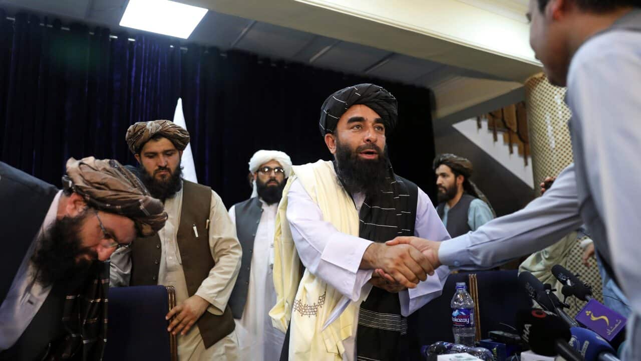 Taliban spokesman Zabihullah Mujahid, centre, shakes hand with journalist after his first news conference, in Kabul, Afghanistan, Tuesday, Aug. 17, 2021.