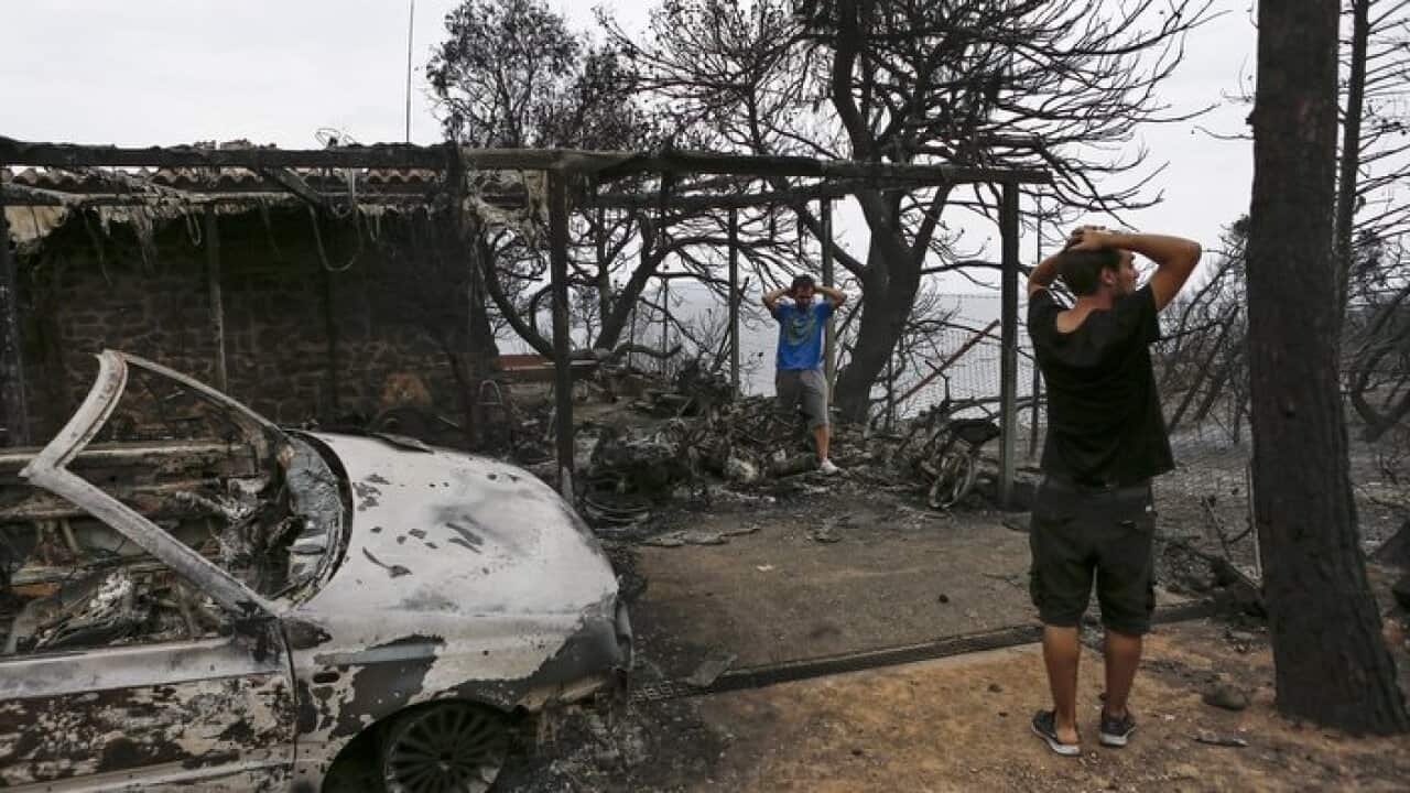 Residents react as they look at their burned house following a forest fire in Mati a northeast suburb of Athens, Greece.