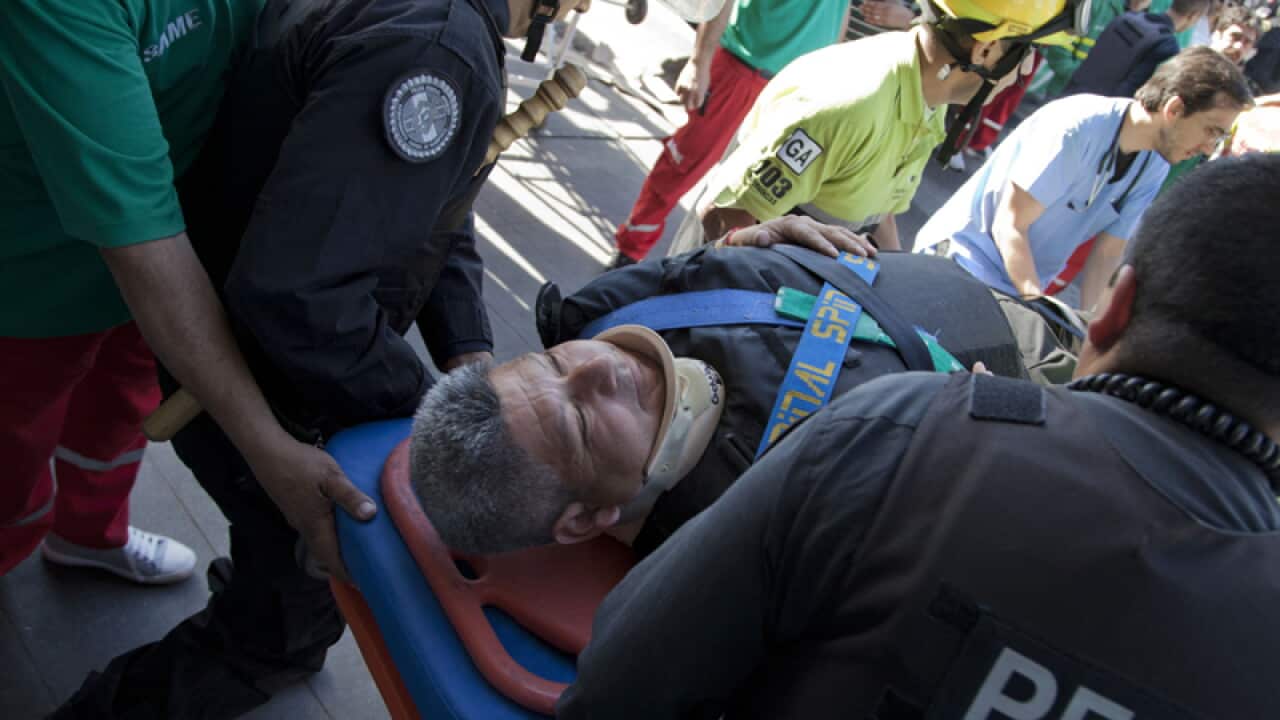 Police and paramedics carry a wounded passenger to an ambulance.