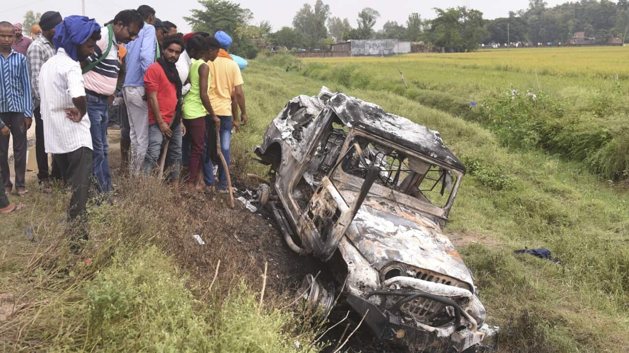 Villagers watch a burnt car which run over and killed farmers on Sunday,
