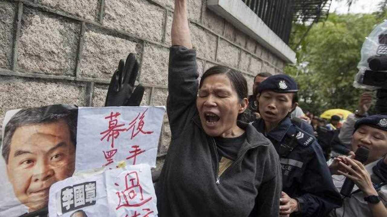 A protesters shouts next to pictures of Hong Kong's Chief Ecexutive Leung Chun-ying and Hong Kong University President Arthur Li, as Hong Kong University students, faculty and alumni protest growing fears of loss of academic freedom and institutional auto