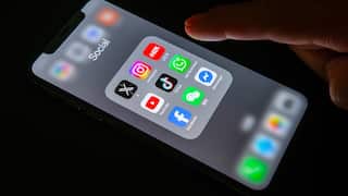 A close image of a phone screen lit up in the dark with a finger hovering above it