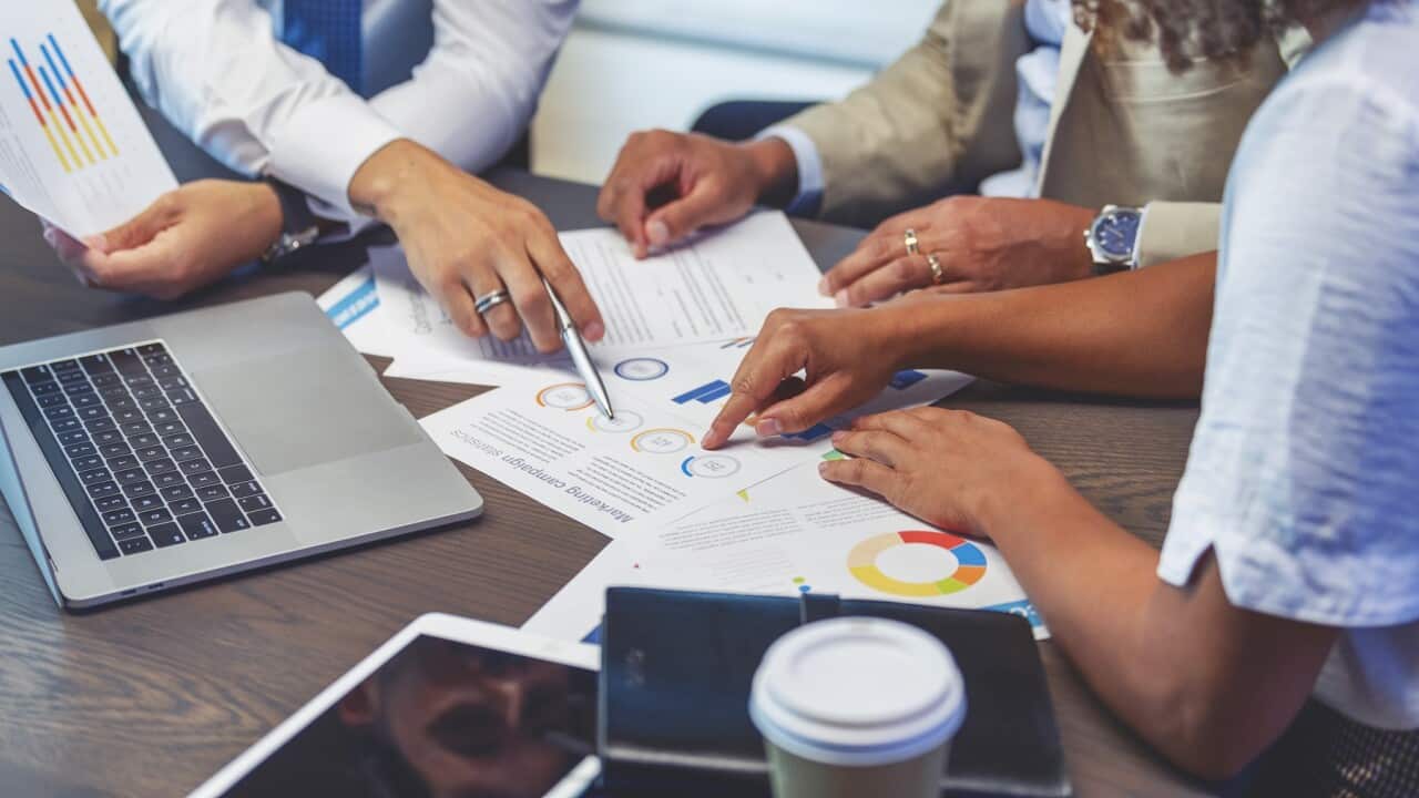 Close up of people pointing to a graph with data.