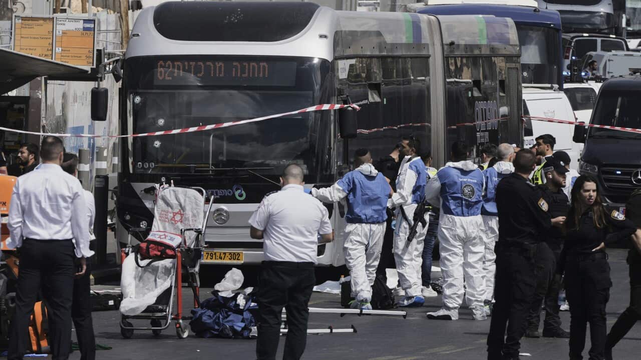 A group of police and emergency workers standing near a bus.