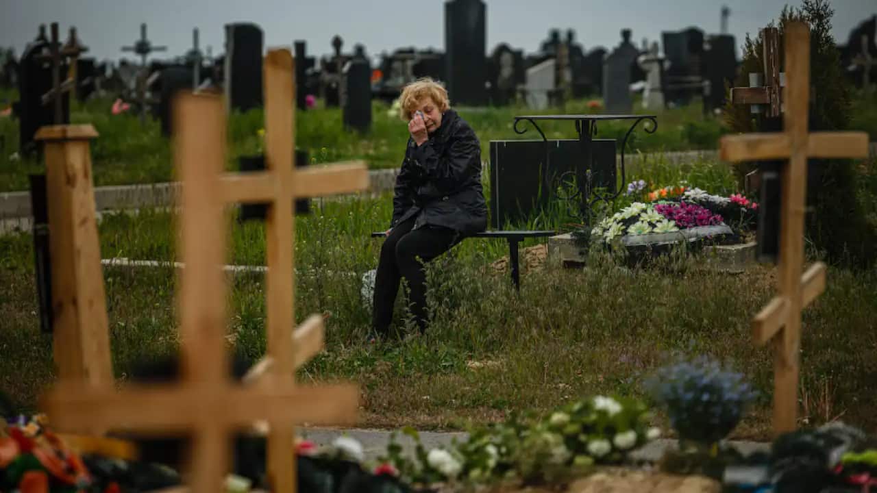 A woman mourns while visiting the grave of Stanislav Hvostov, 22, a Ukrainian serviceman killed during the Russian invasion of Ukraine, in the Kharkiv cemetery.