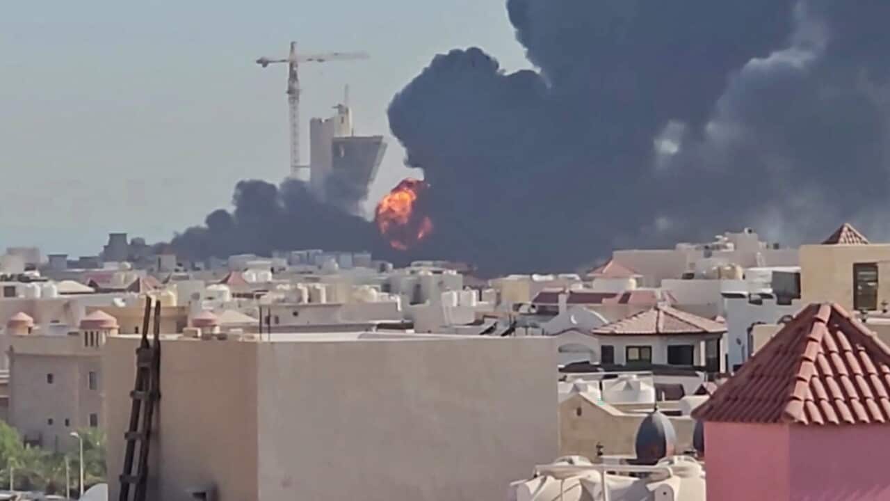 A massive ball of fire and a thick plume of black smoke erupt near a construction site behind a residential neighborhood.