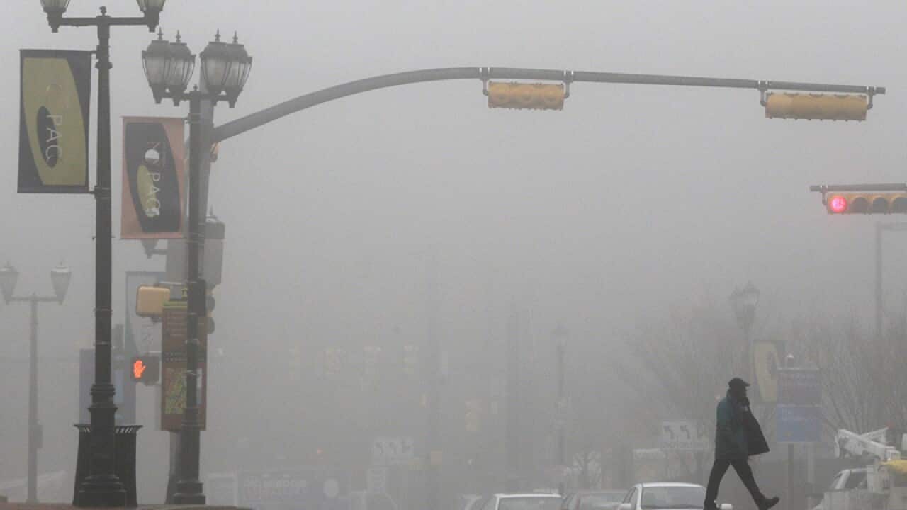 A pedestrian crosses the street as fog blankets downtown Newark, N.J.