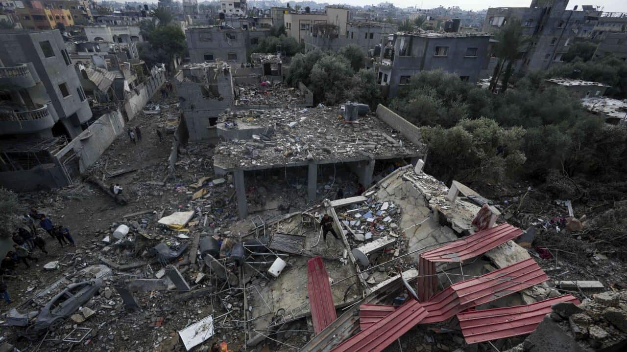 People walk around rubble and the remnants of a building destroyed in an air strike in Gaza