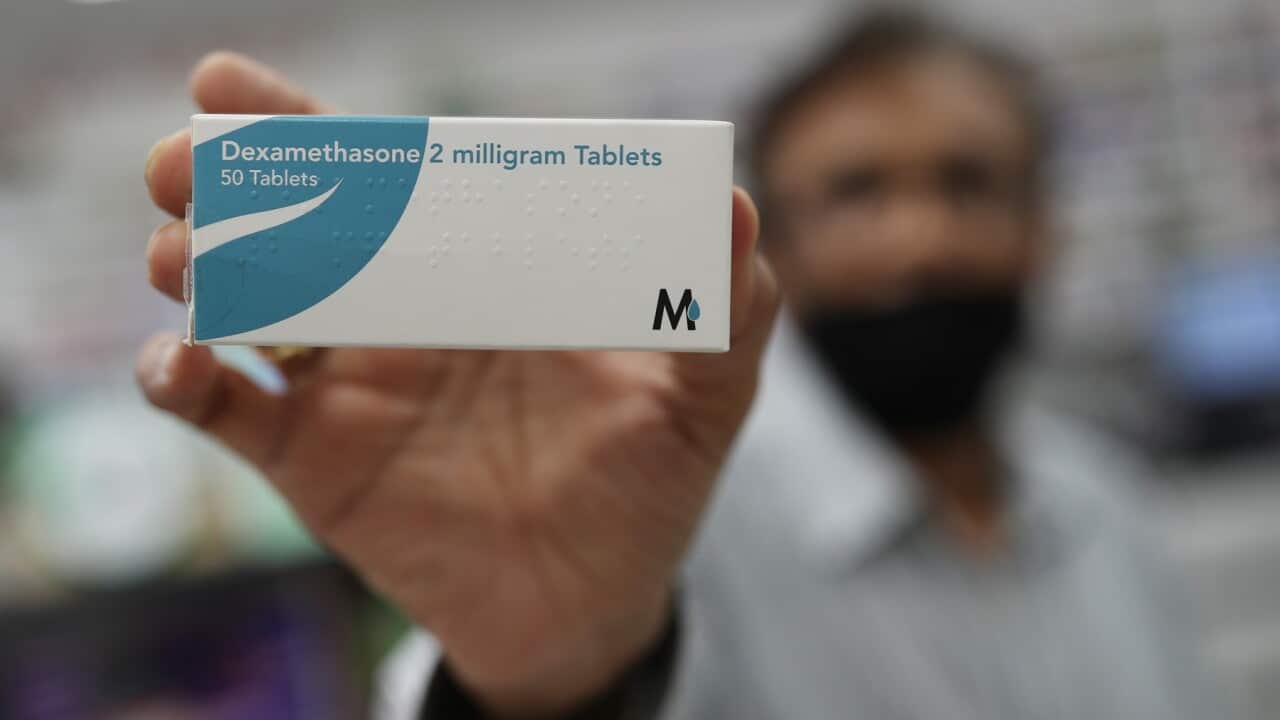 A member of staff at a pharmacy in London holds a packet of anti-inflammatory drug dexamethasone.