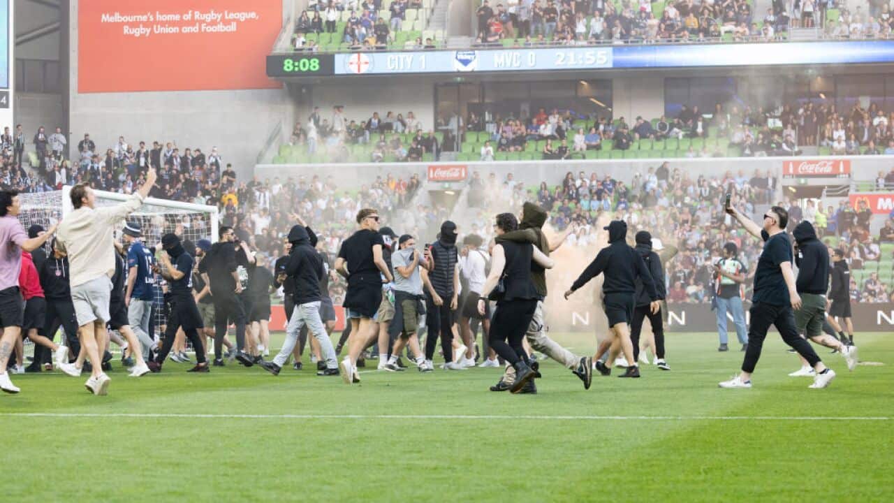 Fans invade a football pitch.