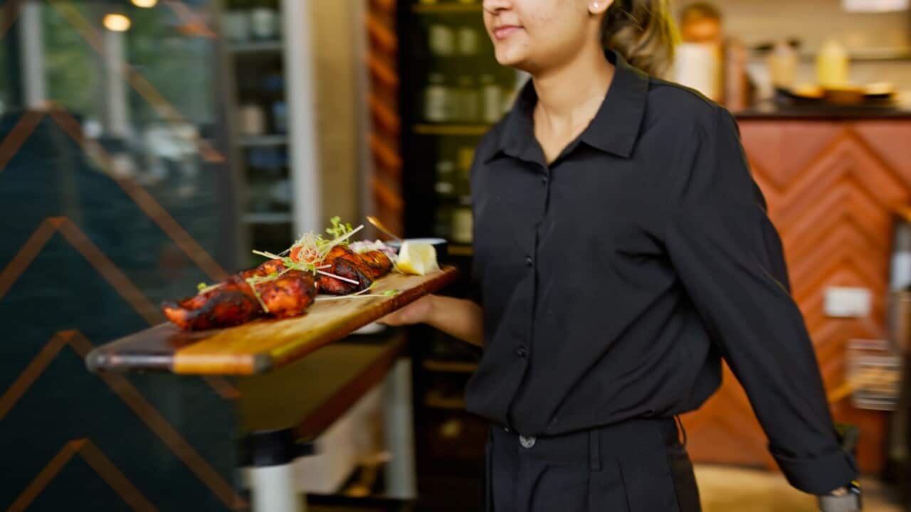 Young Waitress of Indian Restaurant Brings Tandoor Chicken out