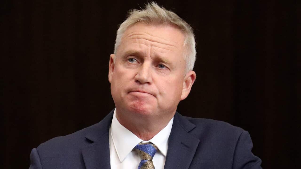 A man in a blue suit, white shirt and blue and gold tie
