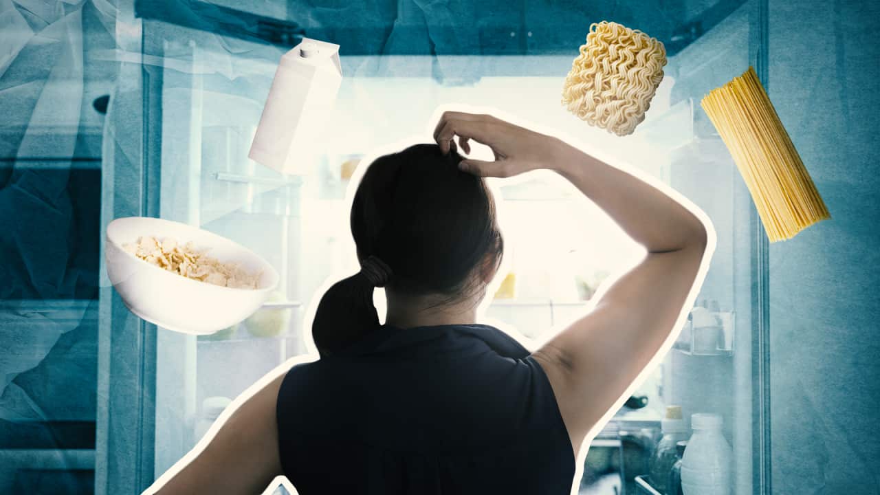 A woman looking into a fridge. Food items like cereal, pasta and milk are floating above her head.