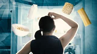 A woman looking into a fridge. Food items like cereal, pasta and milk are floating above her head.