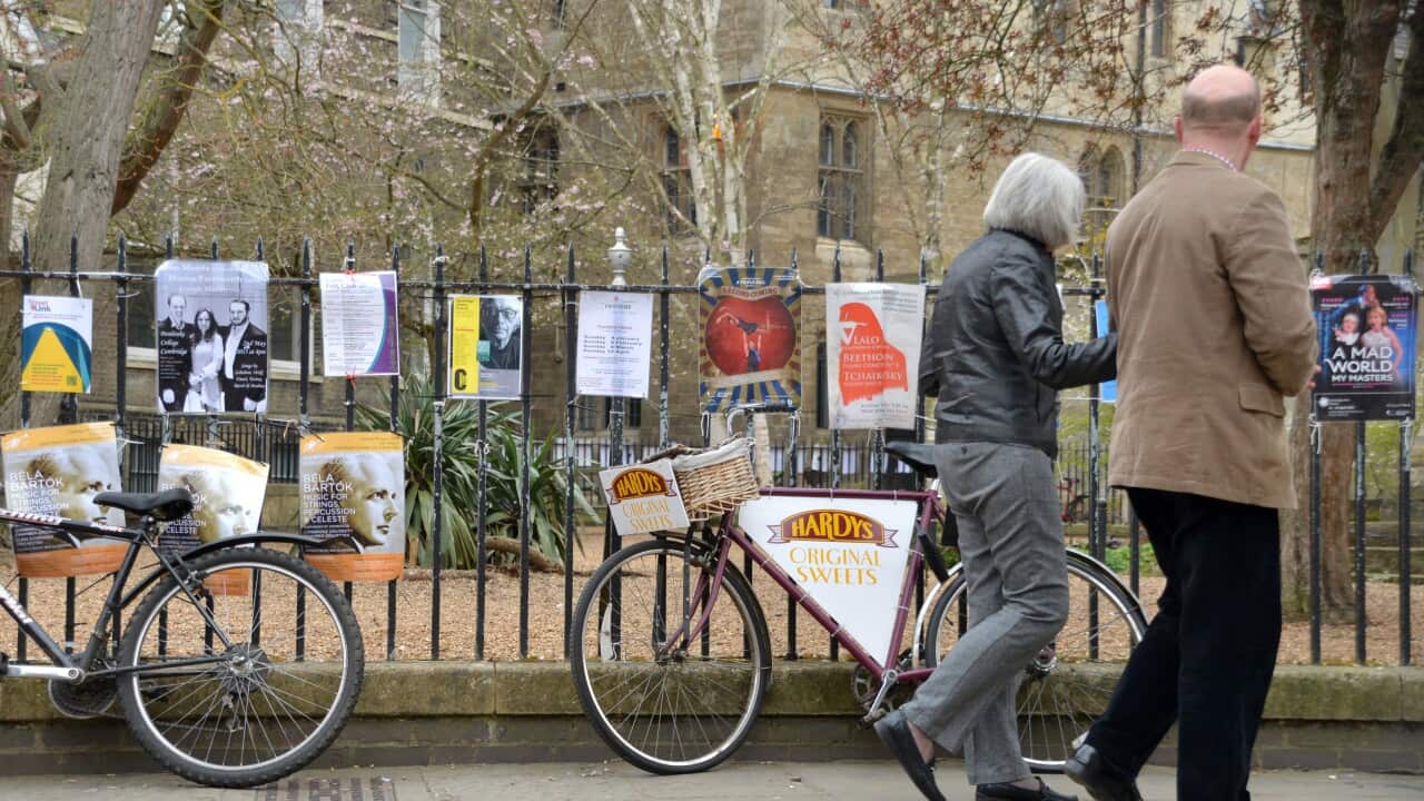 An elderly couple walk past bicycle chained up to a fence along St John's Street in Cambridge.