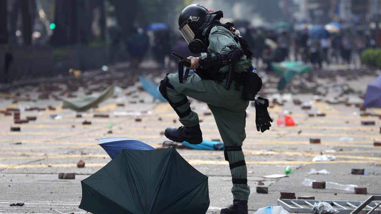A riot police officer stomps on an umbrella used by pro-democracy protesters in 2019 (AAP)
