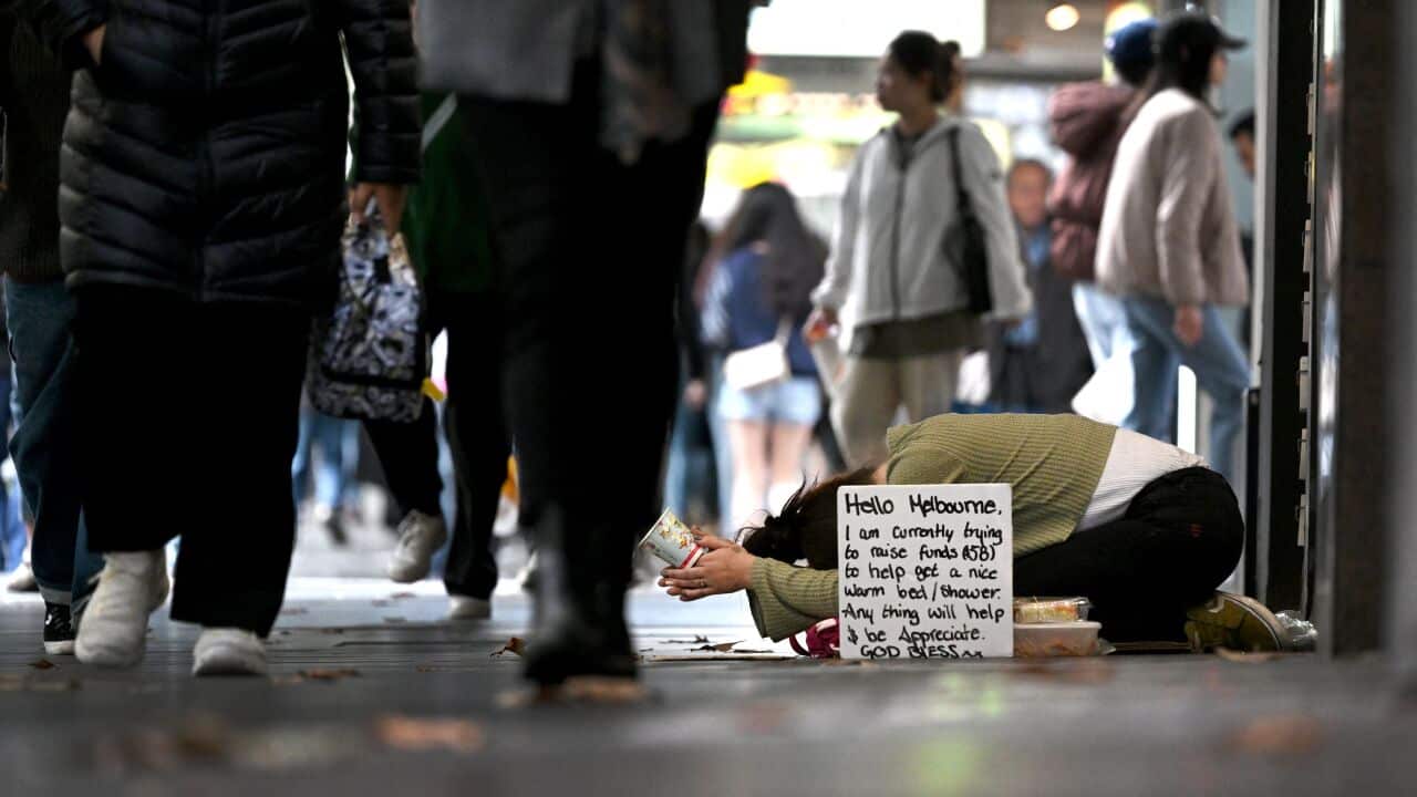 Homeless woman in Melbourne on the ground hoping for help from people passing by