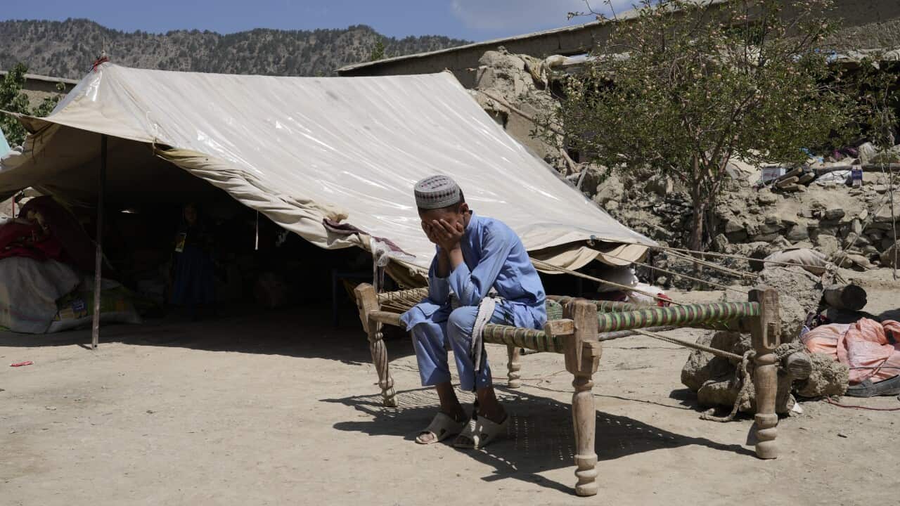A boy sits on a makeshift bed.