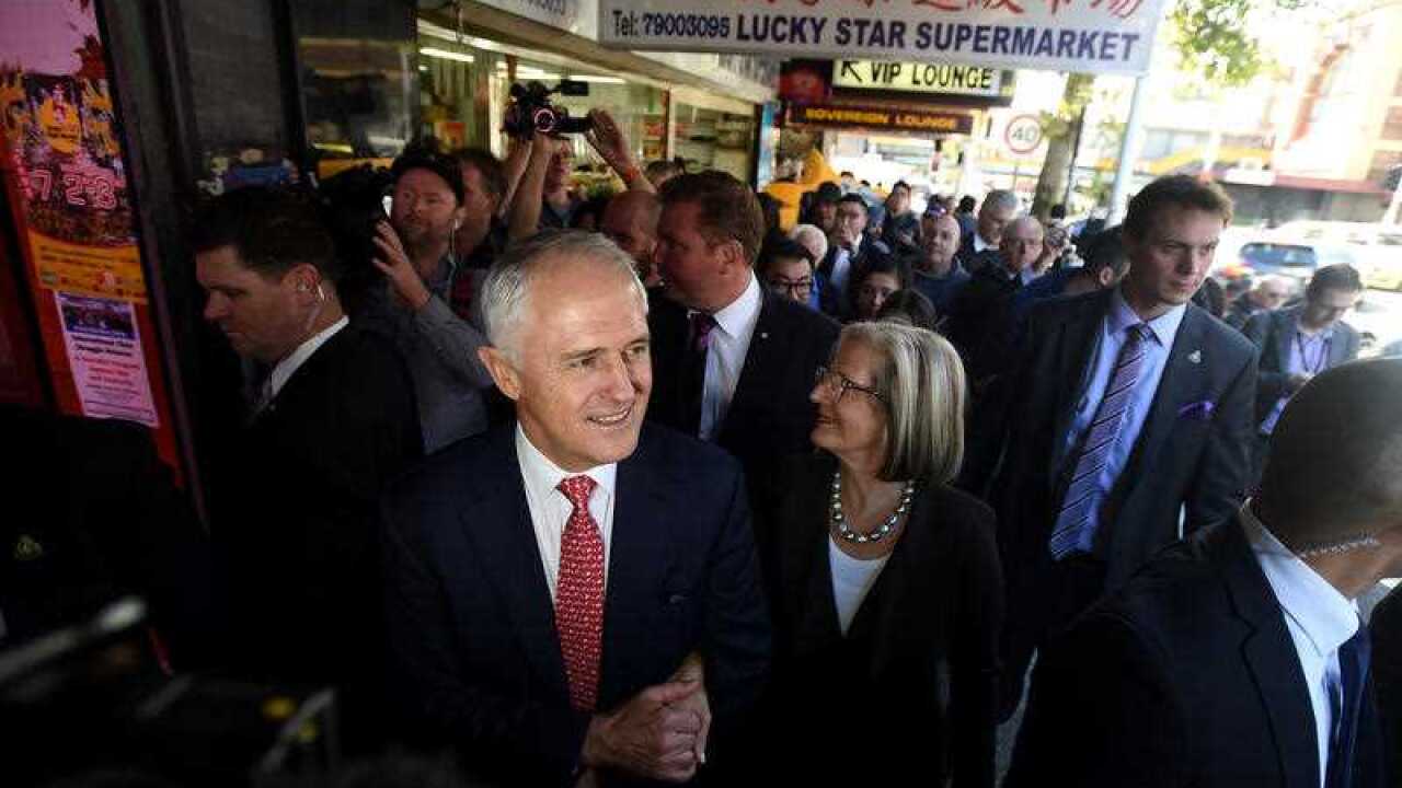 Australian Prime Minister Malcolm Turnbull and his wife Lucy walk past the 'Lucky Star Supermarket' during a street walk with local MP Craig Laundy in the electorate of Reid in the Sydney suburb of Burwood