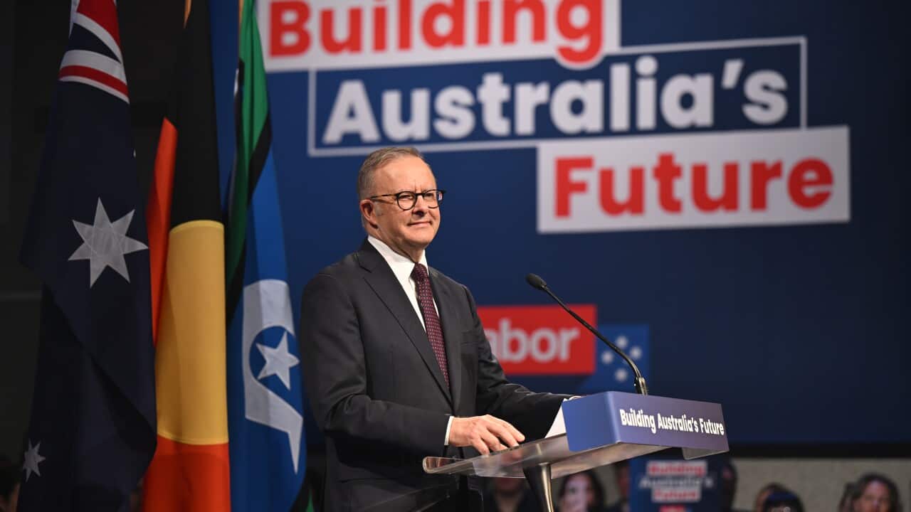 Anthony Albanese stands on a podium addressing a crowd.