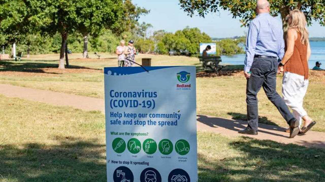 A couple walks past a sign informing population about coronavirus.