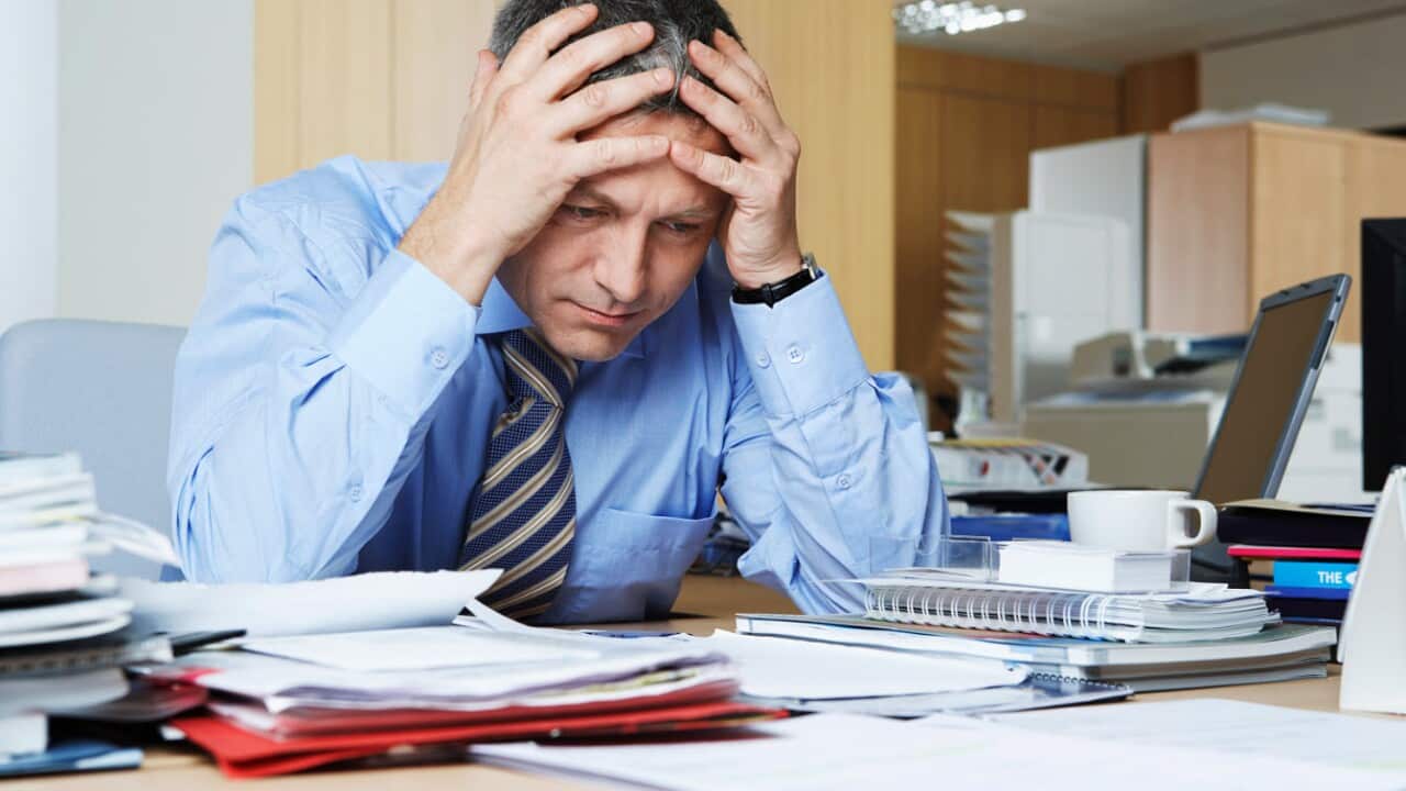File photo: businessman sitting at desk with head in hands