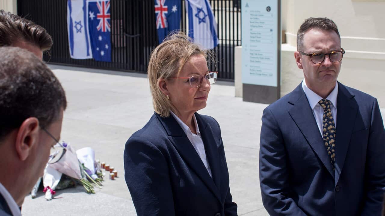 A woman in a blazer is standing next to a man in a suit at the Bondi terror attack site.