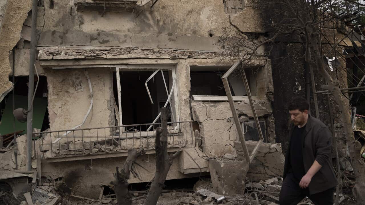 A man walks past a building that is in ruins.