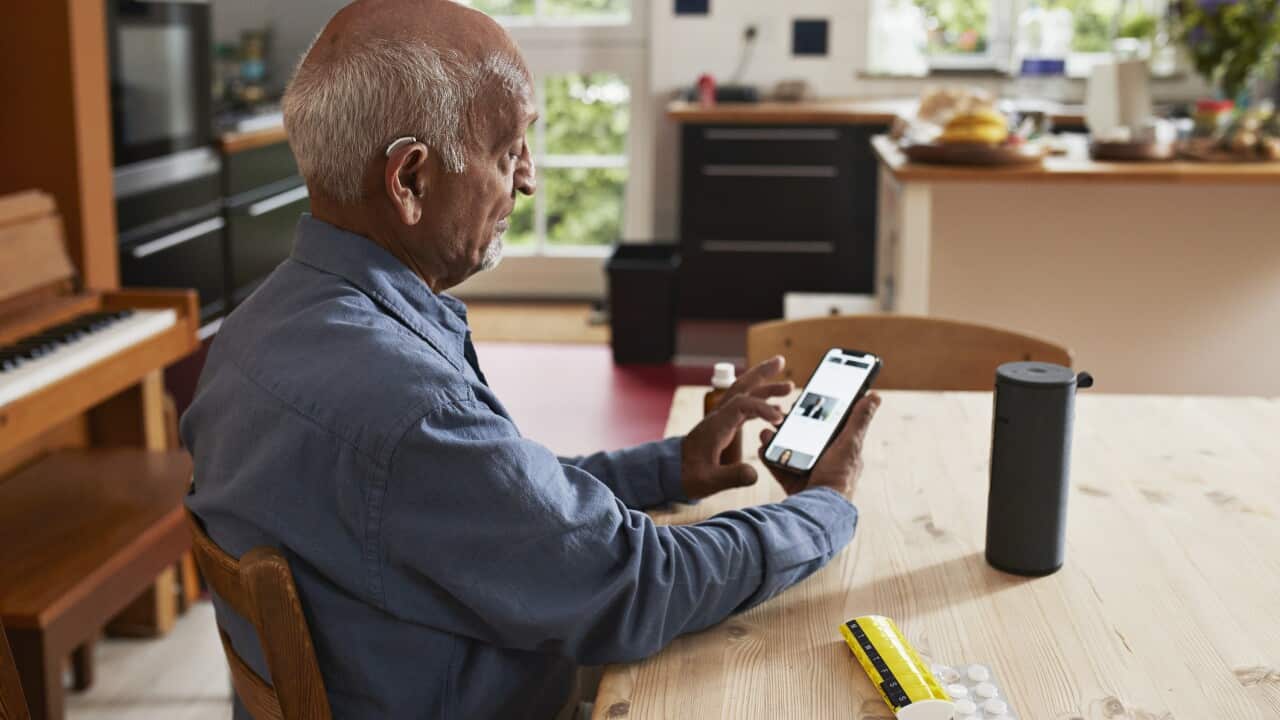 Senior man using smart phone at table