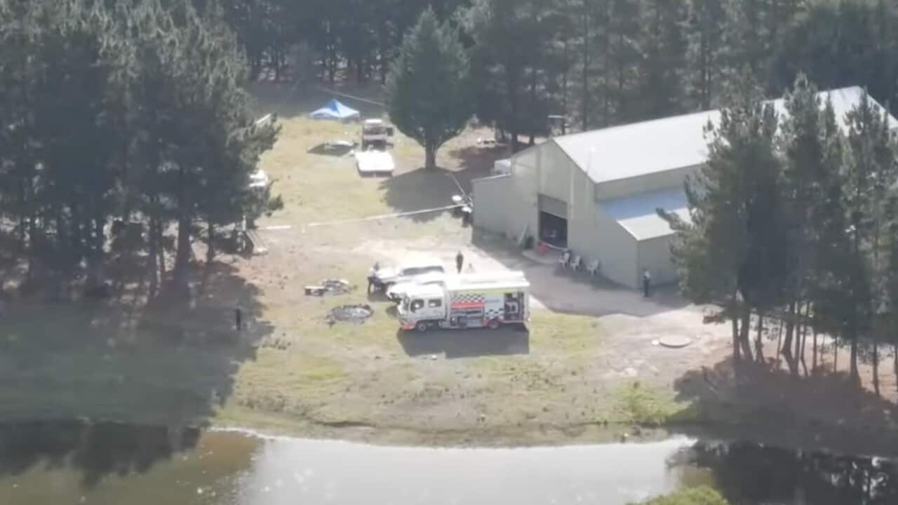 An aerial view of an ambulance at a rural property surrounded by trees and a canal.