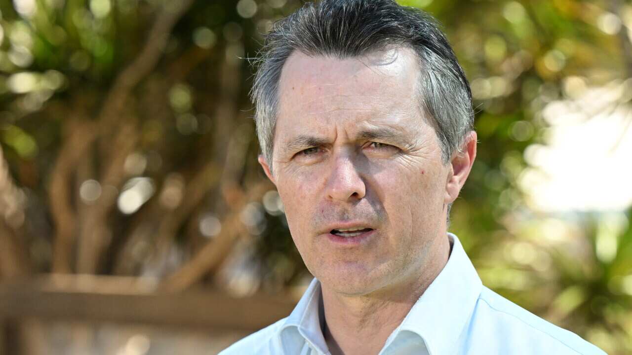 A man wearing a shirt who is speaking while standing outside.