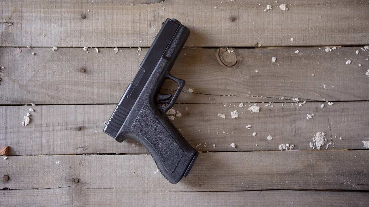 Top view of a gun on a rustic wooden surface