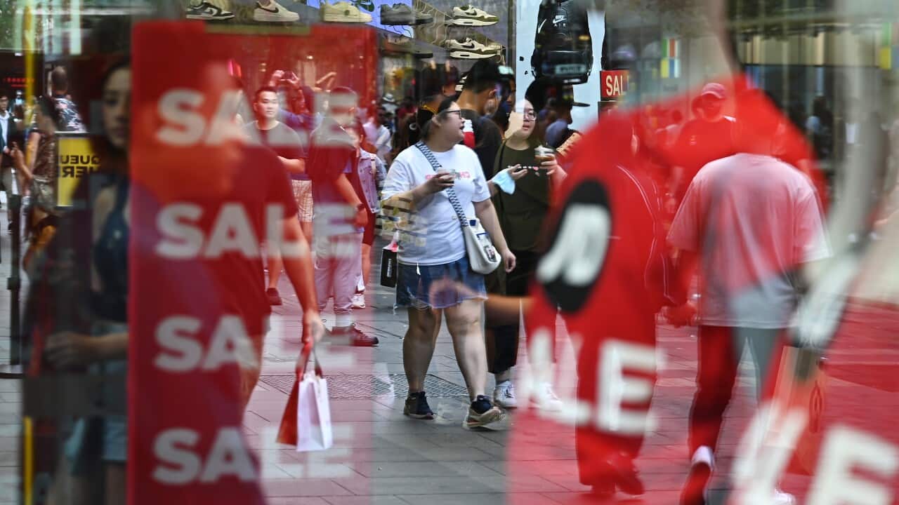 A store front with sales signs and people reflected back
