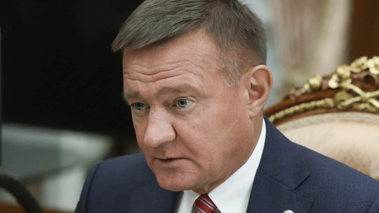 A man with short grey hair sitting on a chair.