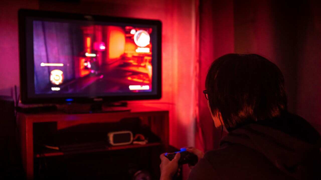 Young male gamer with glasses playing video game at home in the dark room using game console controller watching at LED TV. Gaming and entertainment concepts
