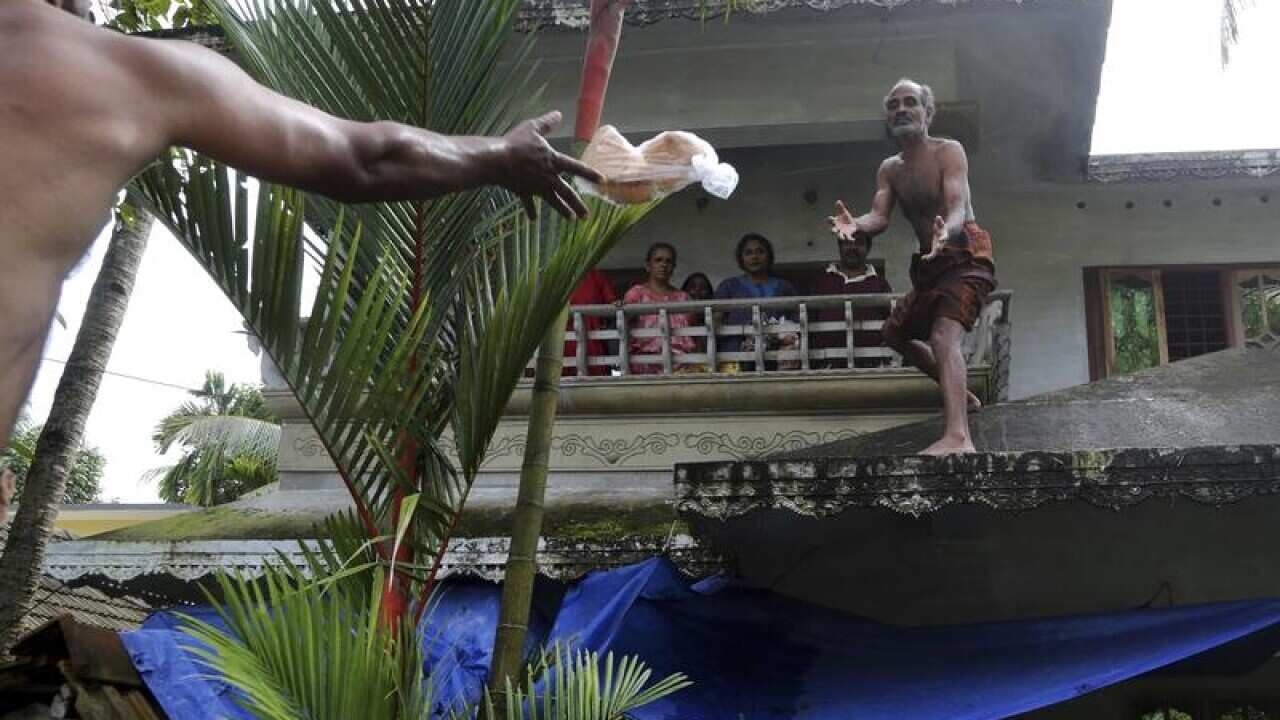 A volunteer throws a pack of bread to a family stranded by the floods