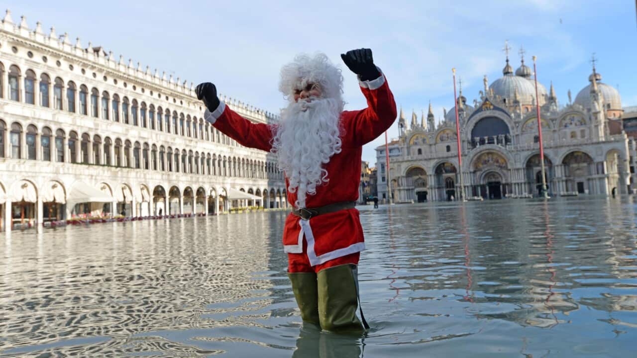 epa08088328 A man disguised as Santa Claus poses in San Marco square flooded by high water, Venice, Italy, 23 December 2019. The high tide reached 144 cm. EPA/Andrea Merola