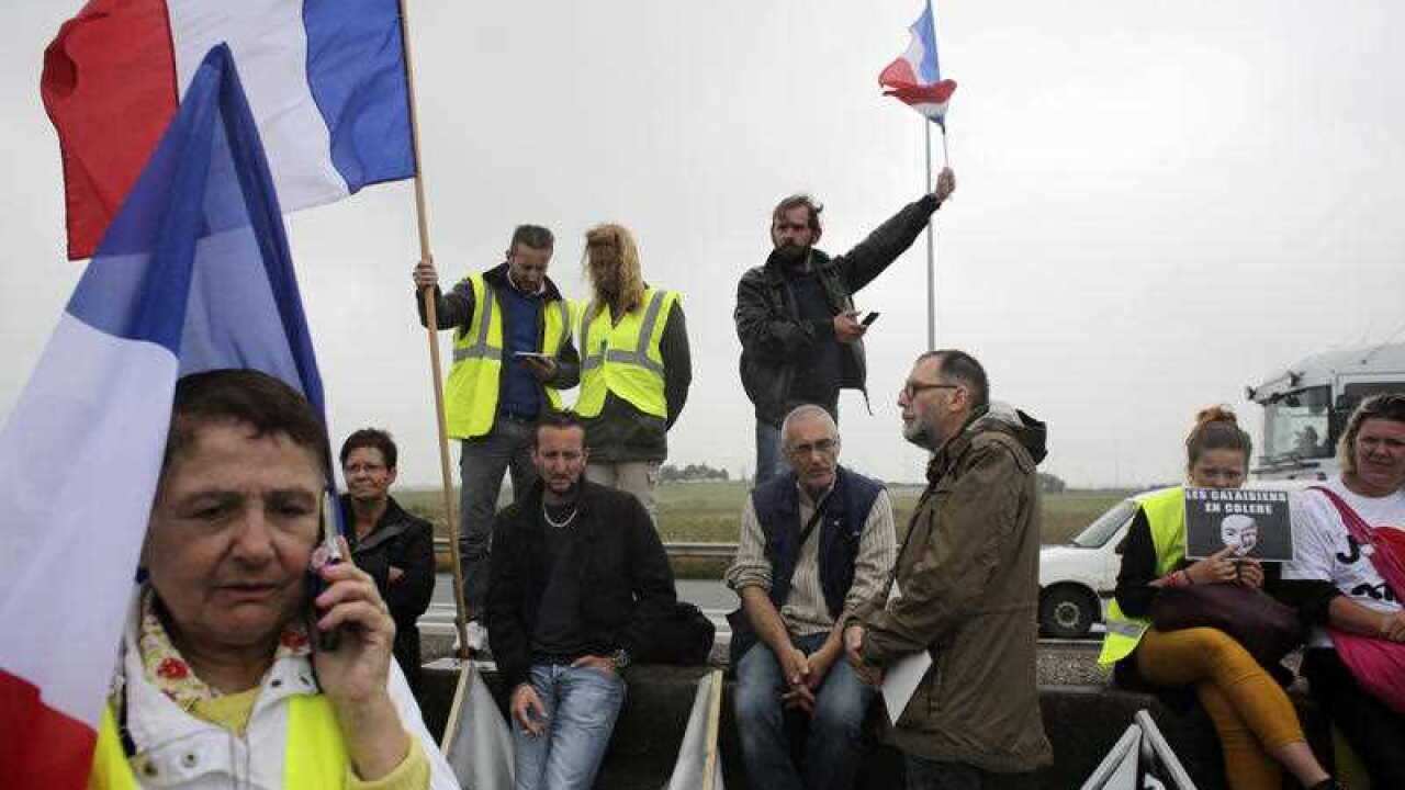 Demonstrators hold French flags as truckers block the highway near Calais, northern France, Monday Sept. 5, 2016.