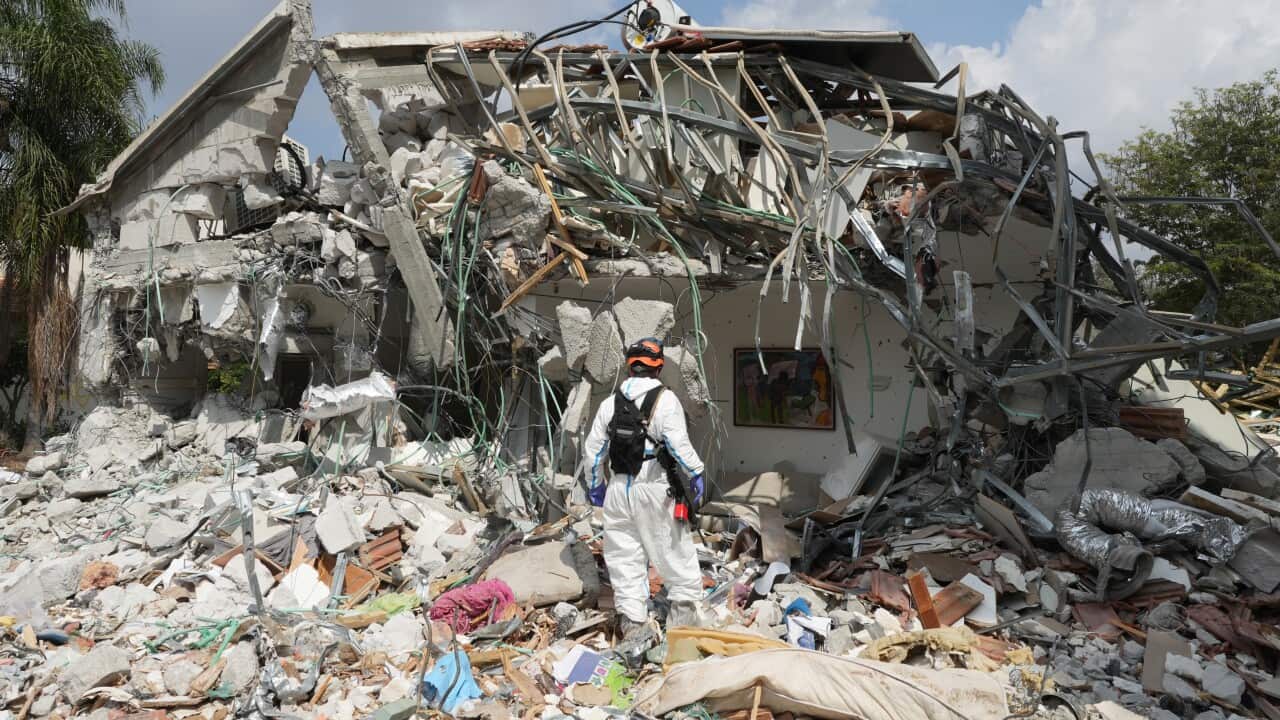 A person inspecting a house that has been destroyed.