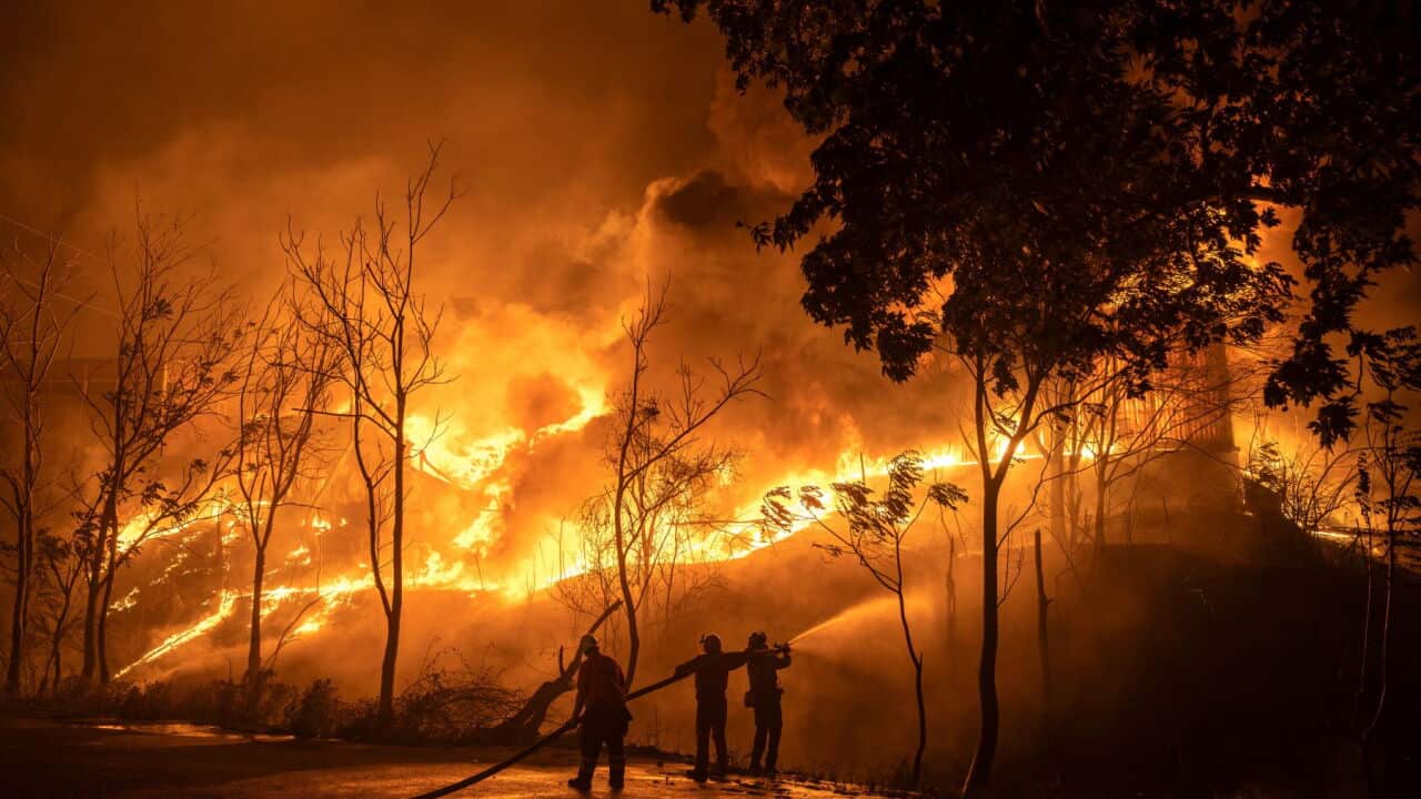 Large fire with silhouette of people in foreground
