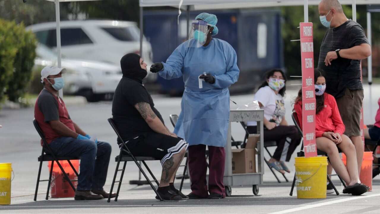 A Florida health care worker administers COVID-19 tests