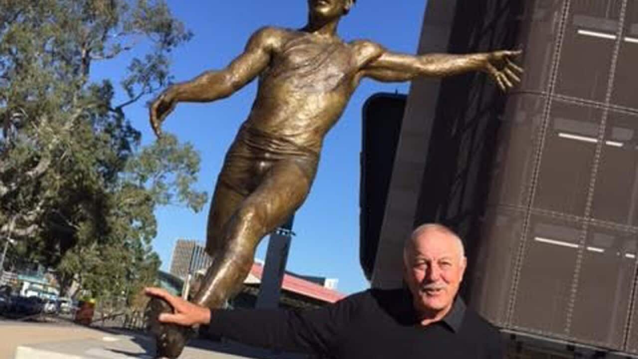 Malcolm Blight poses with his statue