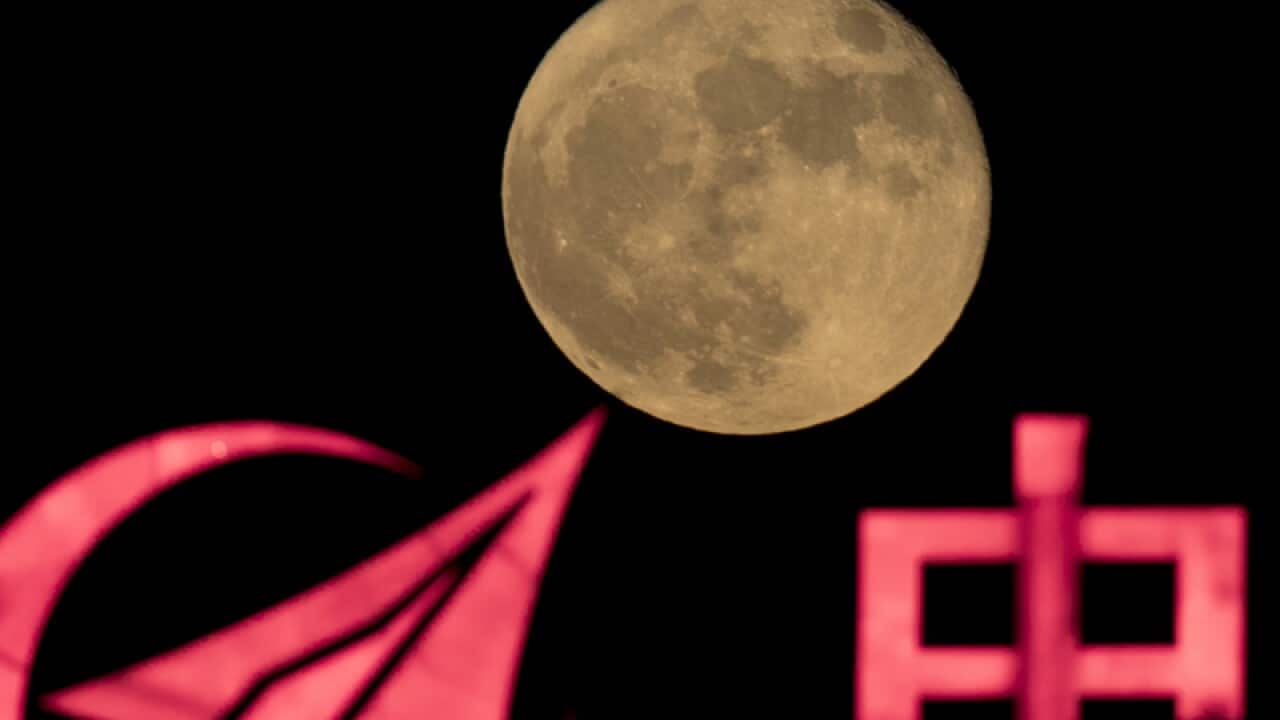 A moon rises over a logo for Aviation Industry Corp in Beijing