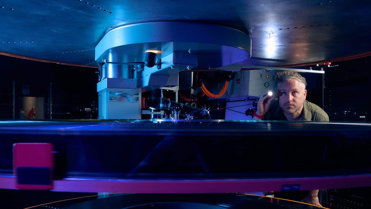 A man looking at the inside of a film reel.