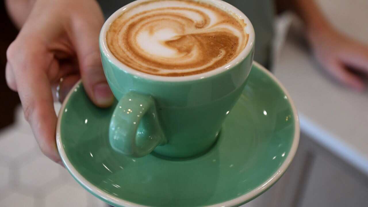 A waitress is seen holding a coffee at a cafe